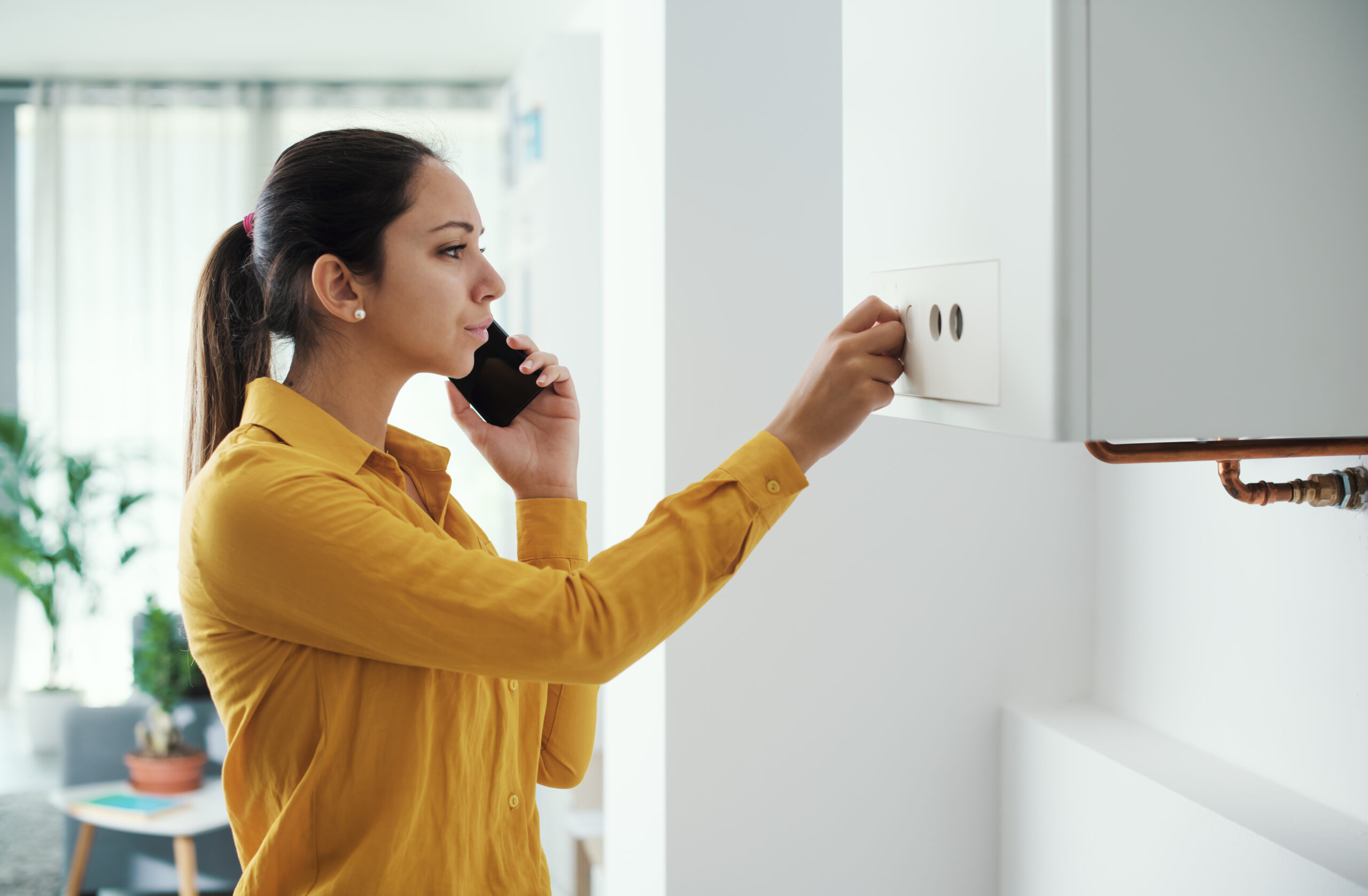 A woman on the phone while adjusting hvac equipment